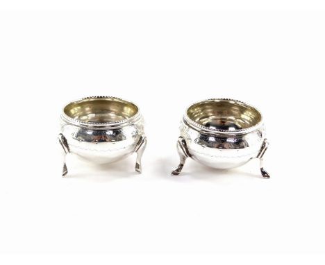 A pair of Victorian miniature circular silver salts, with a reeded collar and hammered detailing with vacant cartouche, on tr