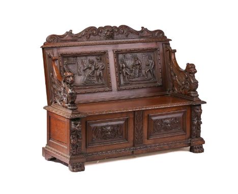 A Victorian 'Jacobethan' carved oak box settle/ hall bench with Elizabethan scenes to the panelled back and scrolling armoria