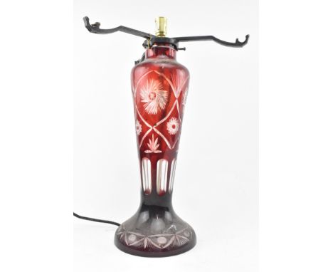 An early 20th century Bohemian ruby flash cut glass lamp base. The base with cast iron shade support (lacking shade), with ta