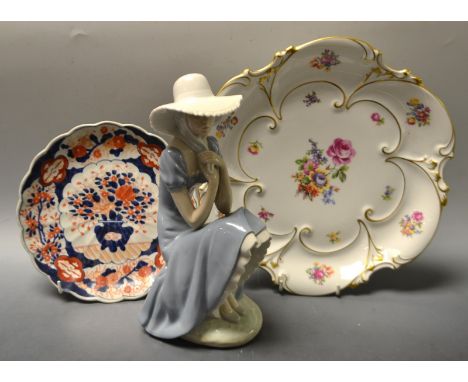 A Nao pottery figure, seated Girl with Bonnet;  a J L Menau porcelain shaped circular dish etc (3) 