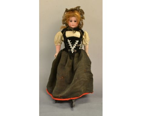 A Continental bisque porcelain doll, brown fixed eyes, closed mouth, brown wig, Austrian/Germanic clothing, stuffed body
