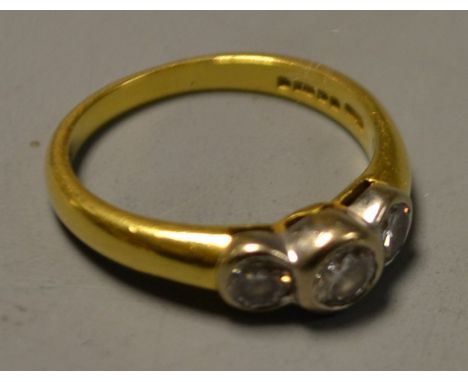 A three stone diamond ring, central round brilliant cut diamond raised above two smaller conforming diamond set shoulders, 18