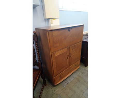 An Ercol Golden Dawn desk, with fall front and cupboards below. 82cm wide