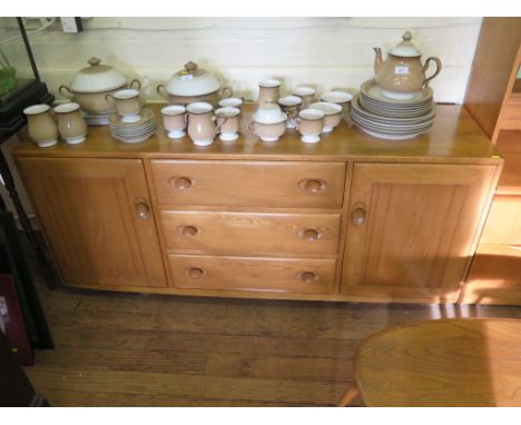 An Ercol ash sideboard with three drawers flanked by cupboard doors, 55cm wide, labelled 