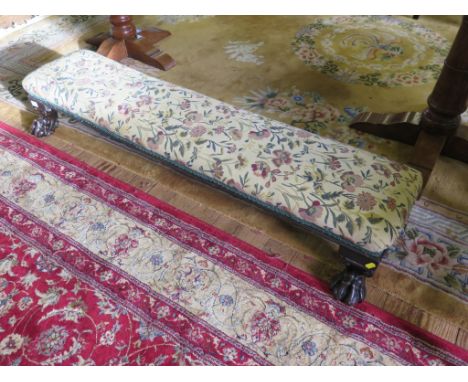 An upholstered long kneeling stool, on lion paw carved feet, 137cm long