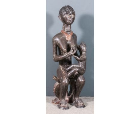 A Ghanaian carved hardwood "Fertility" figure of a mother seated on a stool feeding her baby, 48ins high