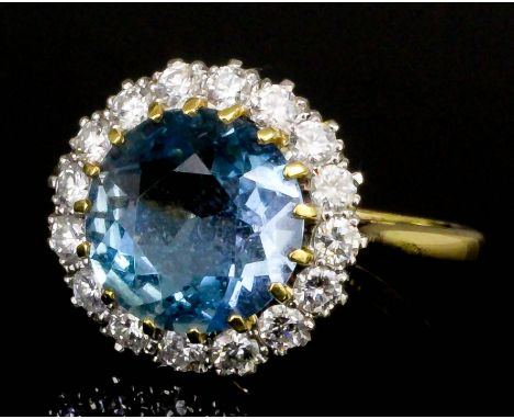 A modern 18ct gold and platinum aquamarine and diamond ring, the circular cut aquamarine of approximately 2.5ct surrounded by