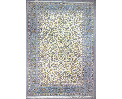 A good Kashan carpet woven in pastel shades with bold trailing leaf ornament, on an ivory ground, within seven stripe borders