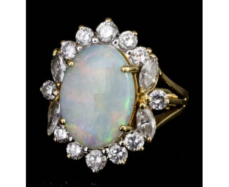 A modern 18ct gold mounted opal and diamond ring, the oval cut opal of approximately 4ct, surrounded by twelve small brillian