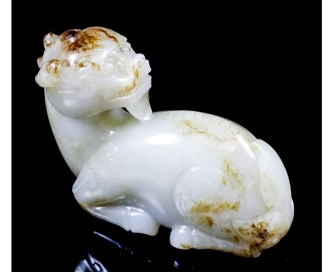 A Chinese pale celadon jade carving of a seated Kylin, his head facing to reverse with brown inclusions to head and rear of b