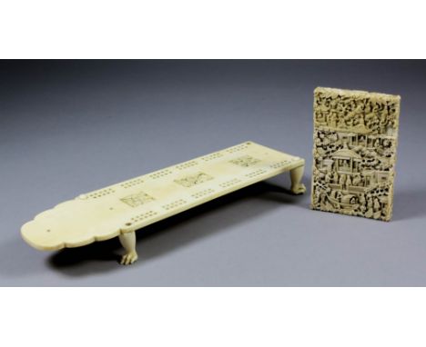 A Chinese ivory rectangular cribbage board with shaped end, the centre carved with three vignettes of figures within pavilion