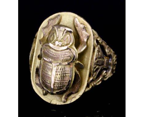 A modern gold coloured metal scarab pattern ring, cast scarab to the central oval panel, within anthemion openwork borders (g