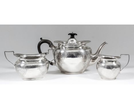 An Edward VII silver oval three piece tea service engraved with leaf scroll and floral ornament, comprising - teapot with woo