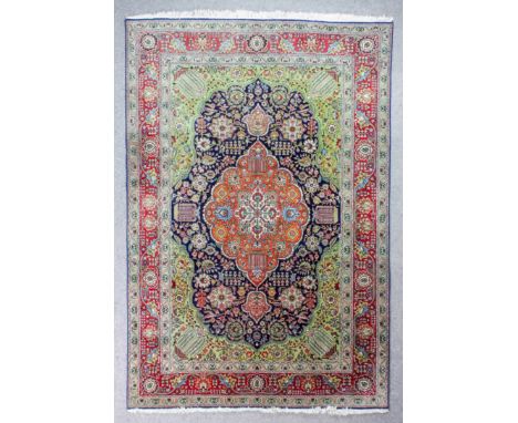 A Tabriz carpet woven in colours with a lozenge shaped centre medallion filled with leaf and floral ornament, similar spandre