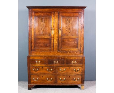 An 18th Century panelled oak bacon cupboard, the upper part with moulded cornice, enclosed by a pair of panelled doors, the b