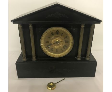 An antique slate mantle clock with pendulum by Ansonia Clock Co, New York. Brass column and engraved floral detail to front. 