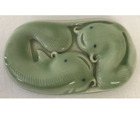 A green porcelain Chinese scroll weight depicting fish. Signed to base with Chinese symbols. Approx. 8.5cm x 5cm x 1.5cm.