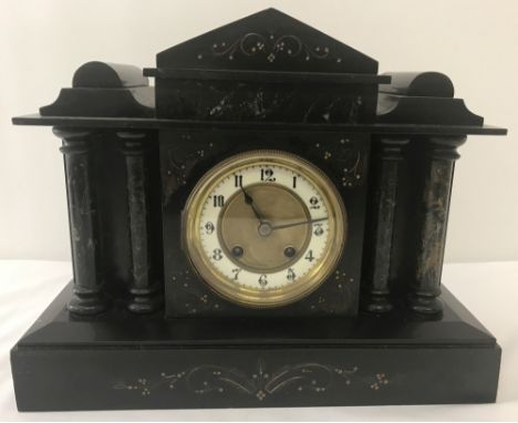 A vintage black slate and marble mantle clock with column detail to front, shaped top &amp; gilt detail. Enamelled outer rim 
