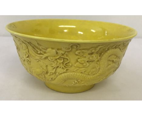 A Chinese porcelain bowl with yellow glaze and dragon detail to outer bowl. With ring mark and signatures to base. Approx. 8c