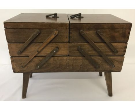 A vintage wooden concertins sewing box on legs. With fold-out trays and brass handles. Approx. H34 x W42 xD21cm