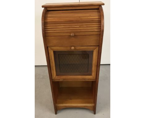 A small light wood cabinet with tambour shutter, pull down cupboard door and open lower shelf.  Approx. 81cm tall x 36.5cm wi