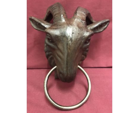 A cast iron door knocker of a goats head holding a ring in its mouth.  Approx. 25cm tall.