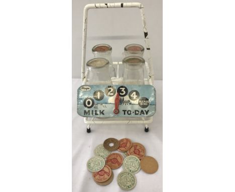 A vintage door stop bottle holder with 4 wide neck milk bottles. Together with 18 vintage cardboard milk bottle tops 