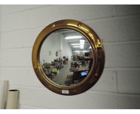 A circular brass port hole design mirror
