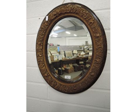 A hallway mirror with oval design bevel edged glass and ornate gilt and plaster frame