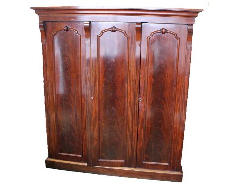 Victorian mahogany triple wardrobe, the step moulded cornice above three doors with scrolled moulding, opening to reveal a fi
