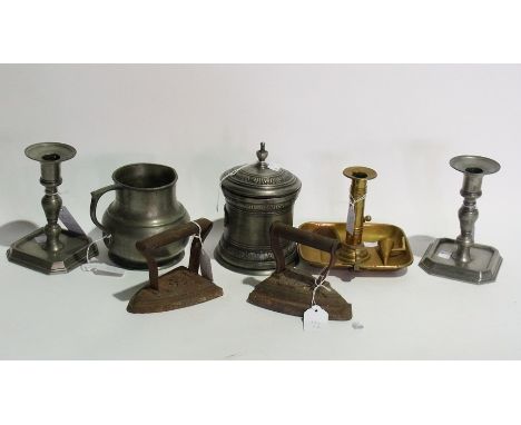Two pewter candlesticks, a pewter jug, a pewter jar. a brass chamber candlestick along with two flat irons (6) 