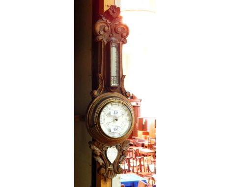 An Edwardian oak aneroid barometer with thermometer, in carved oak surround and with a silvered shield-shaped presentation pl