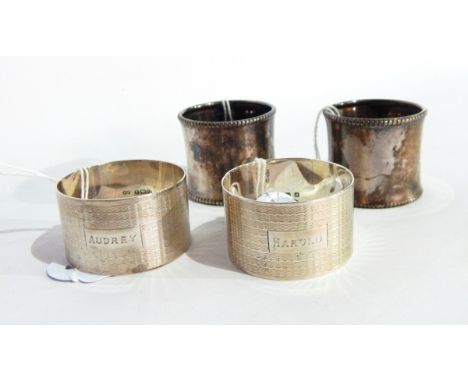 Two cased silver napkin rings of engine turned decoration and a pair of silver napkin rings with bead edges 