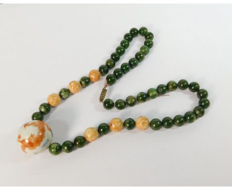 CHINESE NECKLACE. A Chinese necklace comprising green jade beads, six mottled stone beads & a painted porcelain principal bea