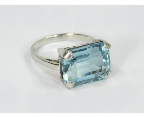 AQUAMARINE RING. A bespoke ring, set a large rectangular, stepped cut aquamarine stone. Unstamped white coloured metal settin