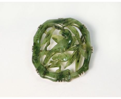 JADE BROOCH. A Chinese pierced & carved green jade brooch, set in 9ct. white gold mount. 5 x 4cm, irregular.  Please note tha