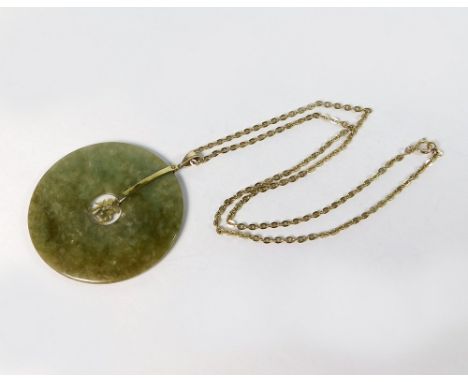 JADE PENDANT. A Chinese jade pendant stamped 14k. on bale. Hung on gold plated chain. Diameter 5.3cm.  Please note that all i