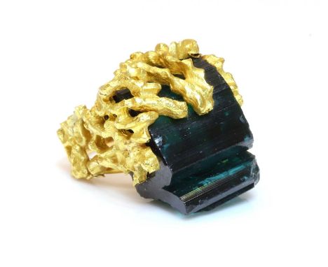 A gold single stone tourmaline ring, c.1970, with a section of uncut tourmaline crystal, to a pierced plate and with naturali