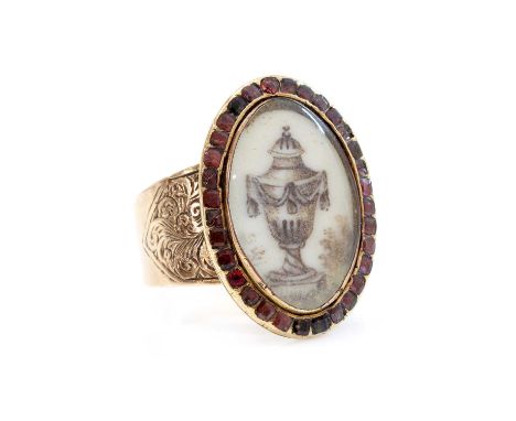 A Georgian garnet set memorial ring,with an oval ivory plaque with an urn, painted en grisaille, beneath a glass cover. A bor