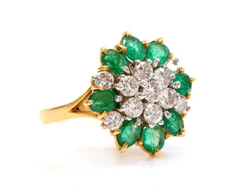 A two colour gold, diamond and emerald cluster ring,with a central daisy cluster of brilliant cut diamonds, claw set in white