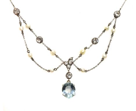 An Edwardian aquamarine, diamond and pearl swag necklace, c.1910, with a later aquamarine pendant drop. An oval mixed cut aqu