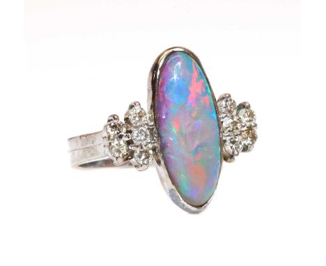 A white gold opal doublet and diamond ring,with an elongated oval cabochon opal doublet, rub set in a portrait position. Five