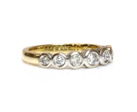 An 18ct two colour gold seven stone graduated diamond ring,with seven graduated brilliant cut diamonds, all rub set in plain 