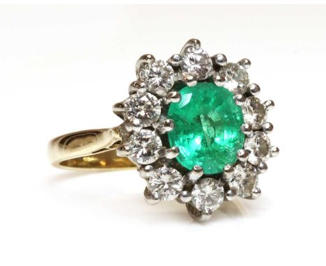 An 18ct gold emerald and diamond oval cluster ring, with an oval mixed cut emerald, claw set to surround of brilliant cut dia