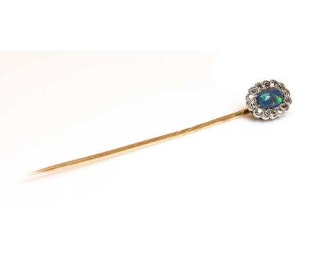 A black opal and diamond stickpin, c.1915,with an oval cabochon black opal, grain set to the centre. A border of old eight cu