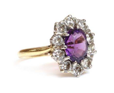 An 18ct gold amethyst and diamond cluster ring, by Arthur &amp; Co., c.1970,with an oval step cut amethyst, claw set and surr