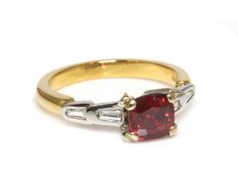 A two colour gold single stone red spinel ring,with diamond set shoulders, with a cushion shaped mixed cut red spinel, with a