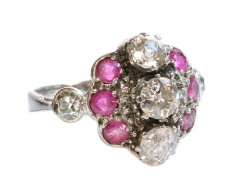 A white gold diamond and ruby cluster ring, c.1935,with three old European cut diamonds, claw set in a fingerline position. T