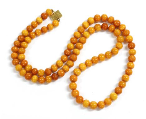 A single row uniform spherical butterscotch amber bead necklace,with eighty eight beads, 11.9 to 13.0mm in size, strung plain