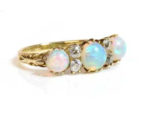 A Victorian seven stone opal and diamond carved head style ring,with a circular cabochon opal at the centre, a pair of old Eu